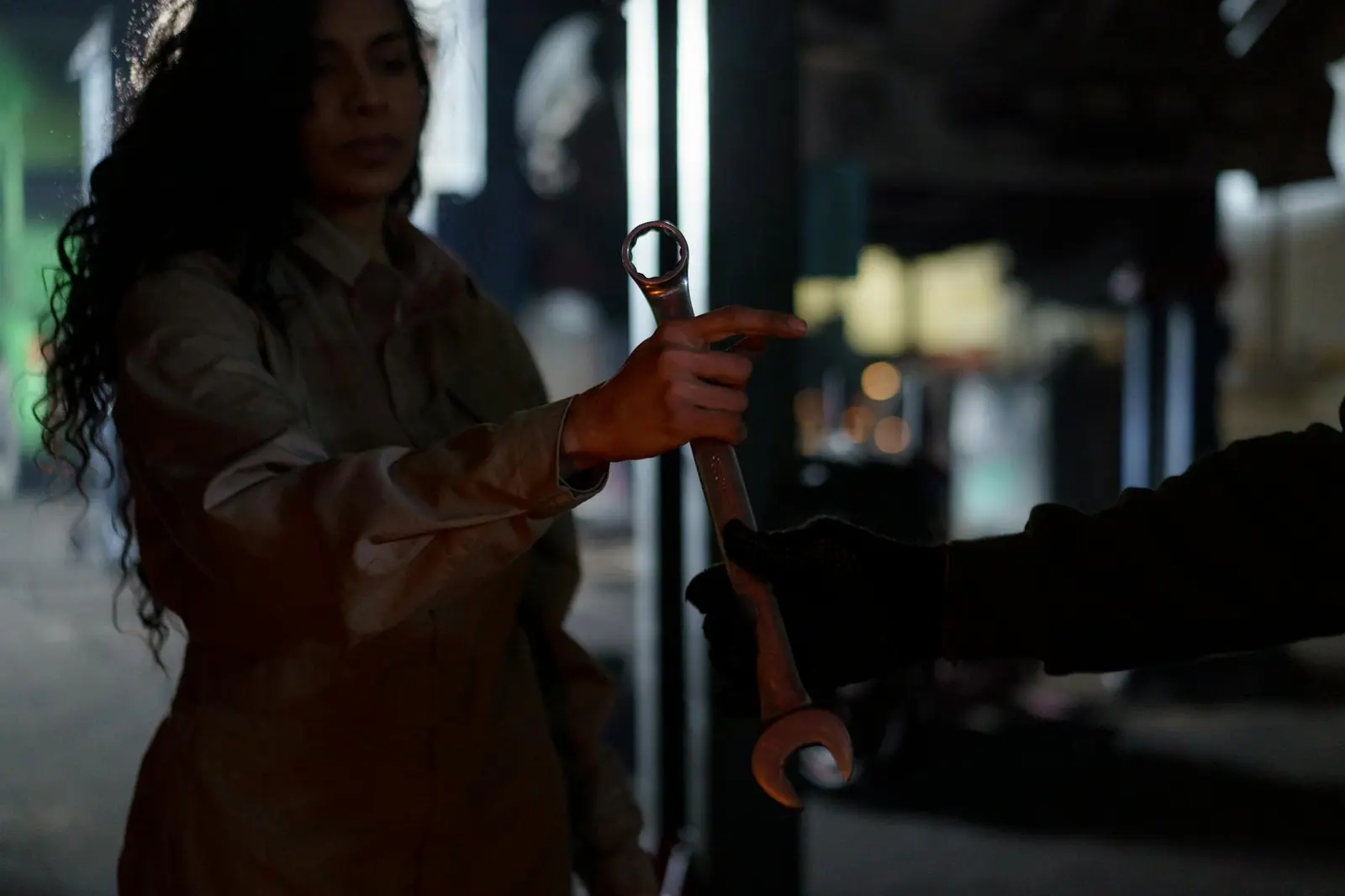 A mechanic's hands holding a wrench over a dark, textured surface